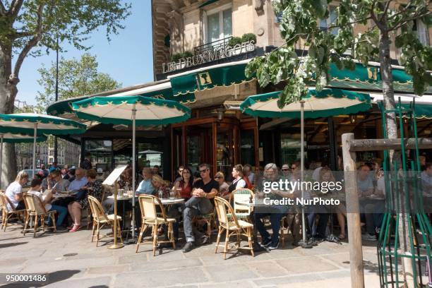 People enjoy the sun and warm spring temperatures at the terrace of the French cafe &quot;Les deux magots&quot; at the Saint-Germain-des-Pres...