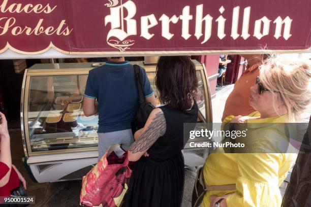 People relax on a warm weather Spring day and queue to buy a luxury Berthillon ice cream on April 22, 2018 on the Ile-Saint-Louis in Paris.