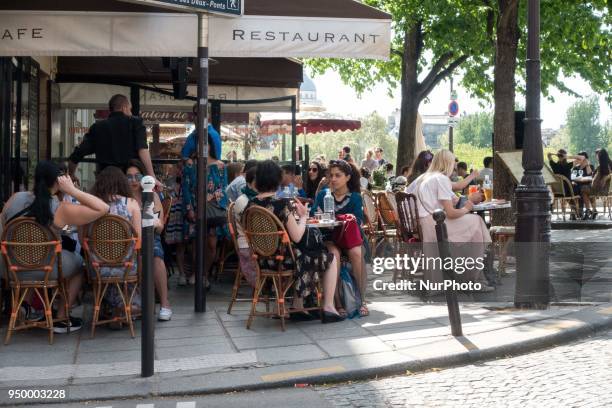 People enjoy the sun and warm spring temperatures at the terrace of the Berthillon cafe at the Ile-Saint-Louis in Paris district in Paris, on April...