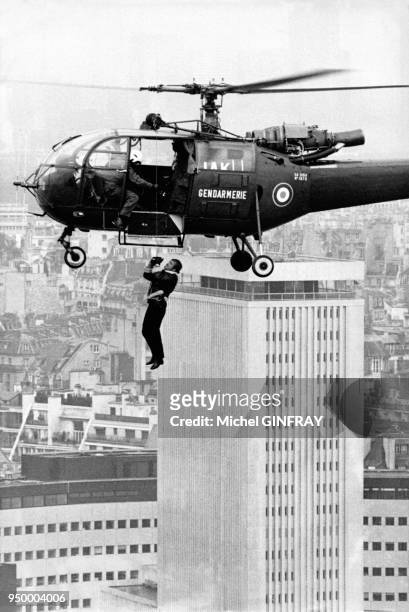 Jean-Paul Belmondo suspendu à un hélicoptère lors du tournage du film 'Peur sur la ville' réalisé par Henri Verneuil en 1974 à Paris, France.