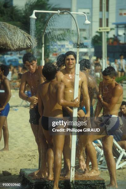 Des baigneurs se rincent dans les douches d'une plage en fevrier 1984 au Bresil.