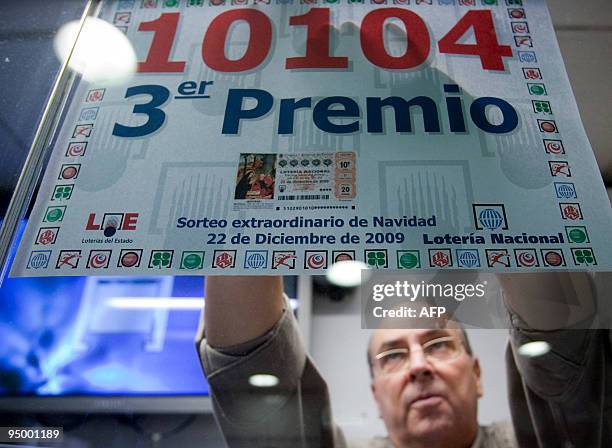 Lottery shopkeepe who sold the third winning ticket puts up the ticket number on December 22, 2009 in Barcelona. Spain's Christmas lottery named "El...