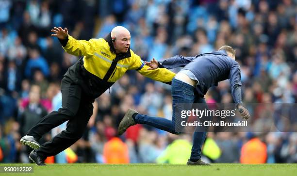 Security chase fans as they invade the pitch following the Premier League match between Manchester City and Swansea City at Etihad Stadium on April...