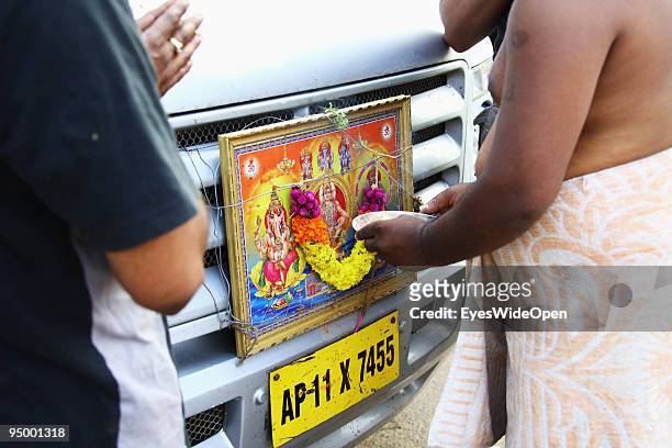 Indian pilgrims praying to the trinity hindu gods fixed at the front of their car on December 12, 2009 in Trivandrum, India.