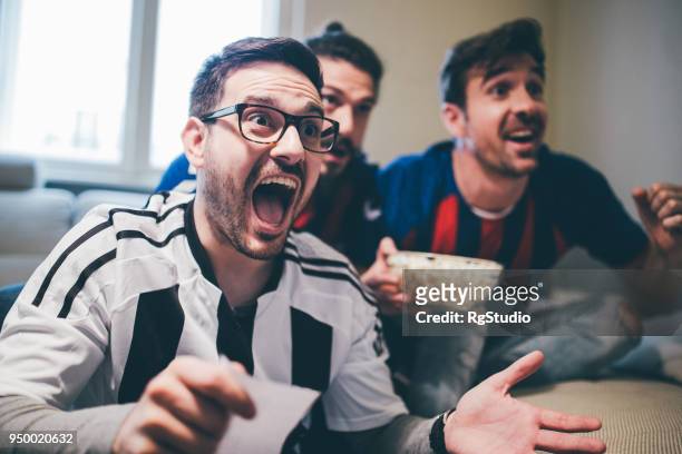 hombre gritando y mirando el juego de futbol con amigos con apuestas deslizar en su mano - match sport fotografías e imágenes de stock