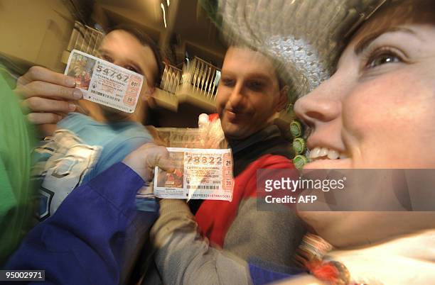 People show their tickets during the draw of the winning numbers of Spain's Christmas lottery named "El Gordo" in Madrid on December 22, 2009....