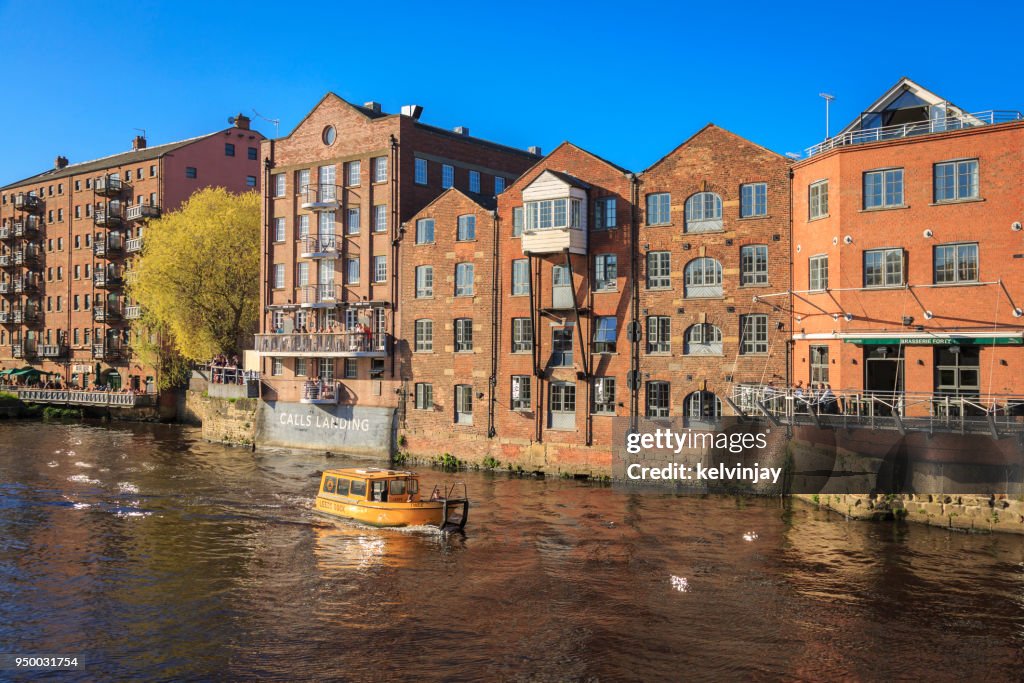 Water Taxi passing apartments on the river Aire in Leeds, Yorkshire.