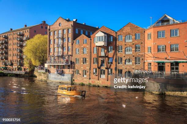 water taxi passing apartments on the river aire in leeds, yorkshire. - kelvinjay stock pictures, royalty-free photos & images