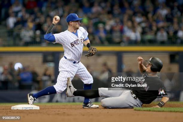Eric Sogard of the Milwaukee Brewers turns a double play past J.T. Realmuto of the Miami Marlins in the third inning at Miller Park on April 22, 2018...
