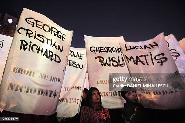 Romanians holds banners reading the names of people killed during the 1989 Revolution reading in Romanian "The heroes never die", during a march...