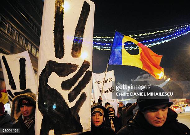 Romanians holds signs depicting the victory sign and wave Romanian flags with holes in the centre during a march commemorating the beginning of...