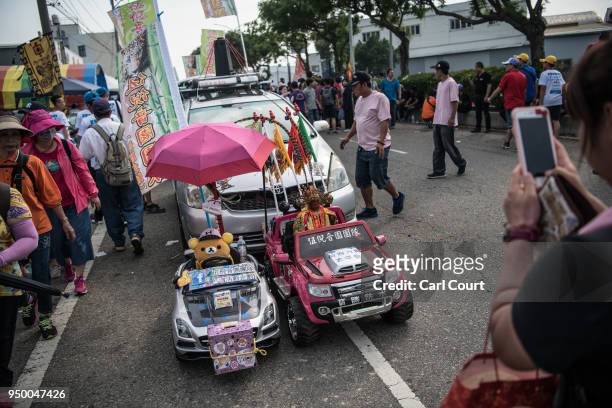 Woman photographs a child's electric car holding a statue of the goddess Mazu during festivities marking the end of the nine day Mazu pilgrimage, on...