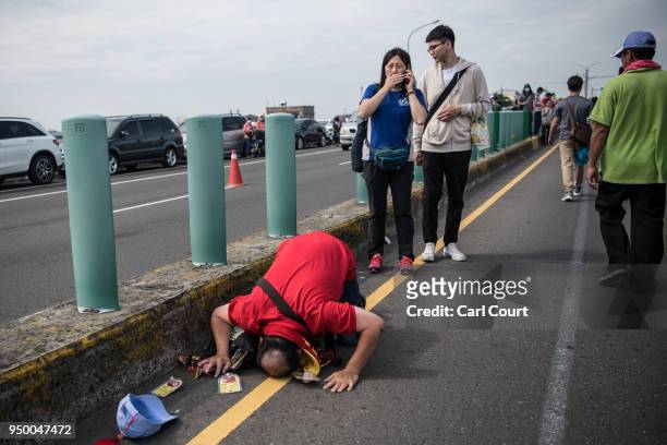 Man prostrates himself in the road in front of a statue of the goddess Mazu as it approaches Jenn Lann Temple on the final day of the nine day Mazu...