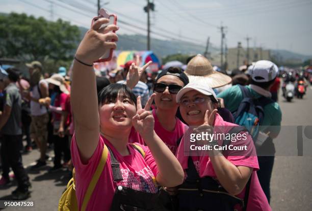Woman take a selfie as they queue to prostrate themselves beneath a sedan chair holding a statue of the goddess Mazu as it approaches Jenn Lann...