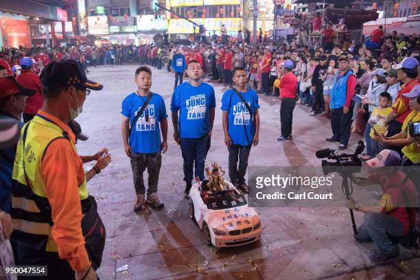 Men pray behind a child's electric car holding a statue of a Taiwanese deity at Jenn Lann Temple during festivities marking the end of the nine day...