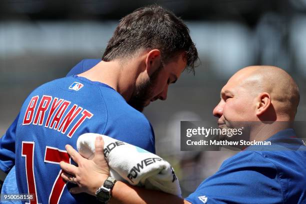 Kris Bryant of the Chicago Cubs is attended to by trainer Matt Johnson after being hit with a pitch in the first inning against the Colorado Rockies...