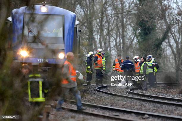 Des pompiers et des gendarmes s'activent autour d'une voiture écrasée après être entrée en colision avec un TER, le 22 décembre 2009 à...