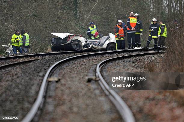 Des pompiers et des gendarmes s'activent autour d'une voiture écrasée après être entrée en colision avec un TER, le 22 décembre 2009 à...