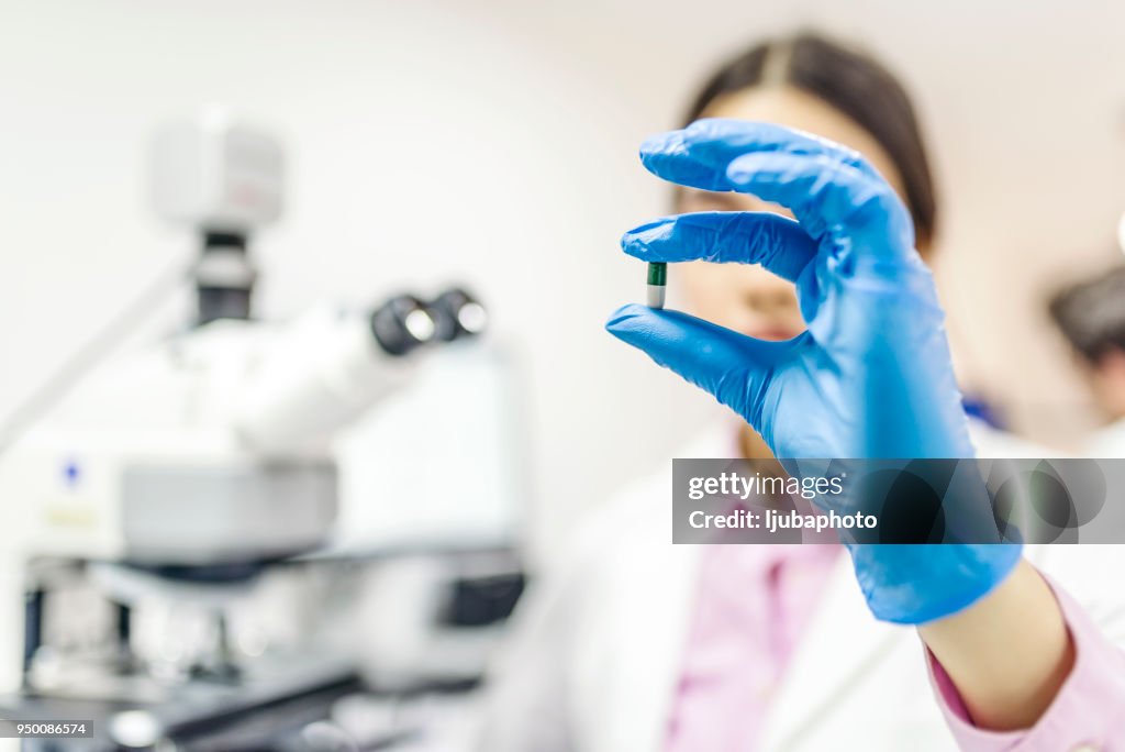 Young attractive female scientist holding a pill