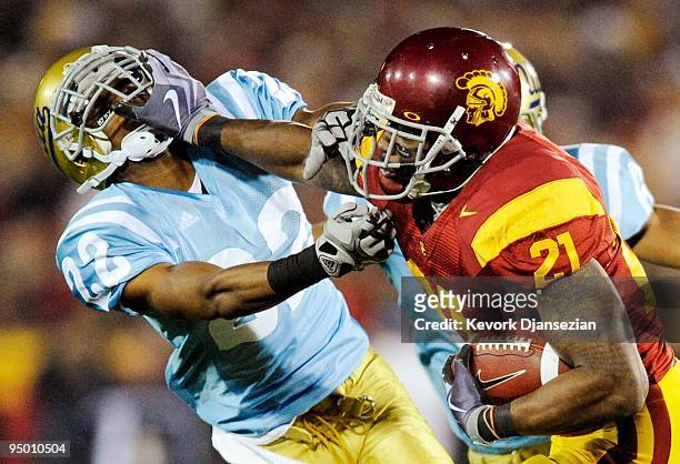 Tailback Allen Bradford of the USC Trojans stiff arms defensive back Sheldon Price of the UCLA Bruins as he runs for a gain during the second quarter...