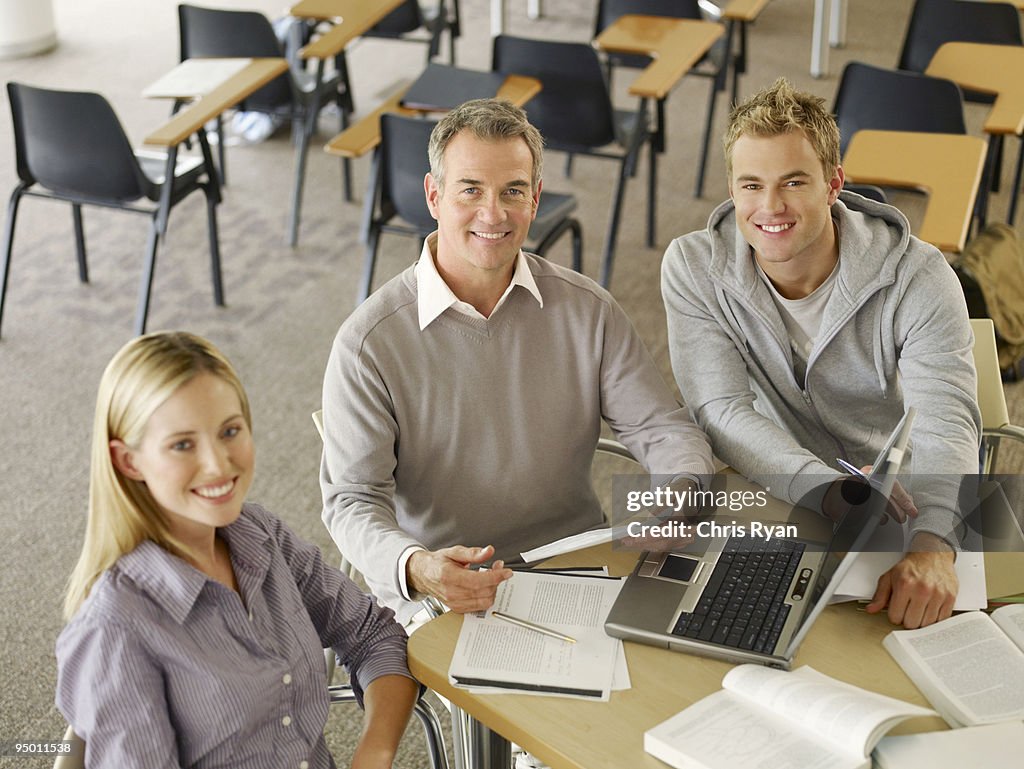 College students and professor using laptop in classroom