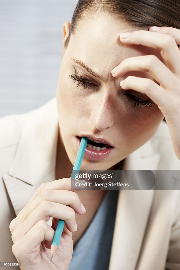 Businesswoman biting pencil
