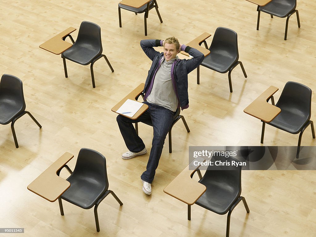 Confident college student sitting at desk in classroom