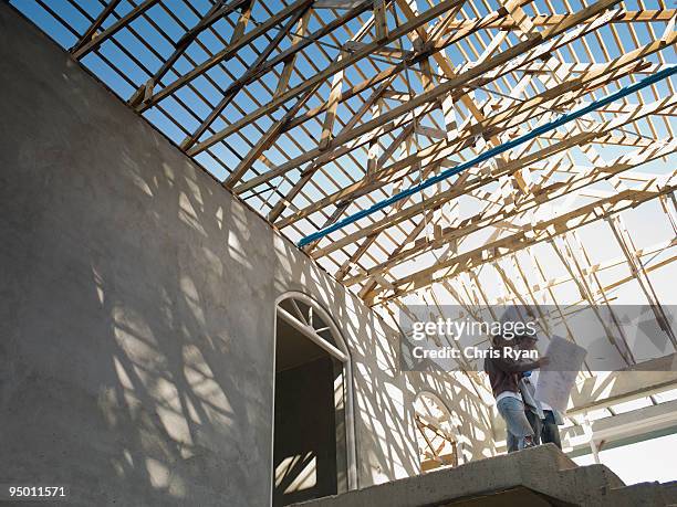 couple looking at blueprints in house under construction - infrastructure development stock pictures, royalty-free photos & images