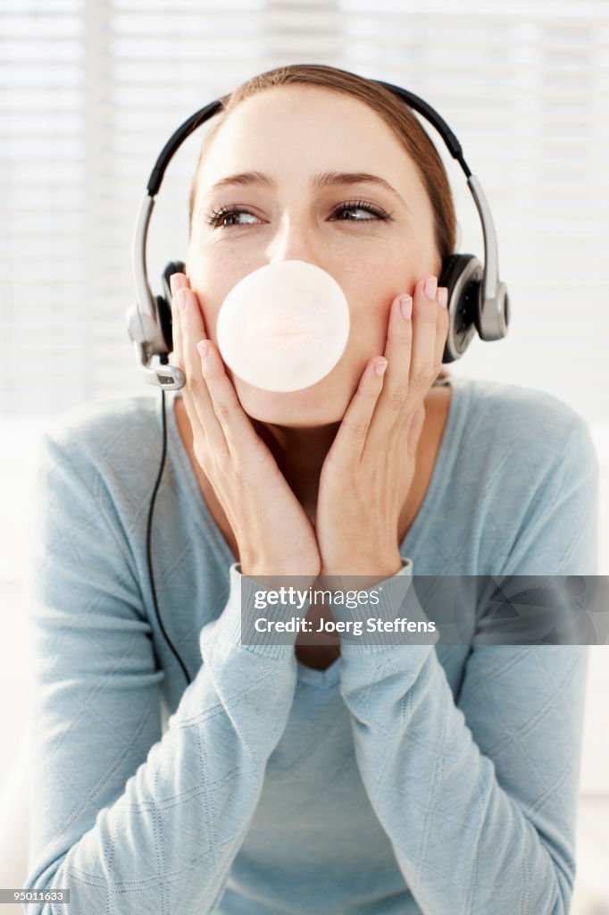 Woman wearing headset and blowing bubble