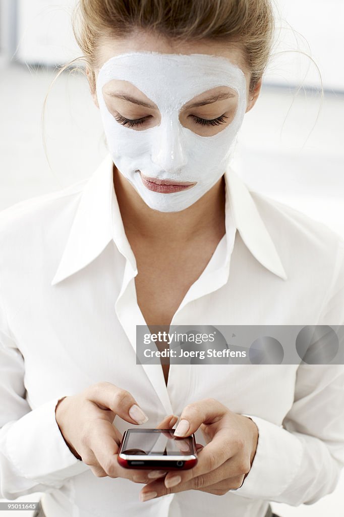 Woman with facial mask using cell phone
