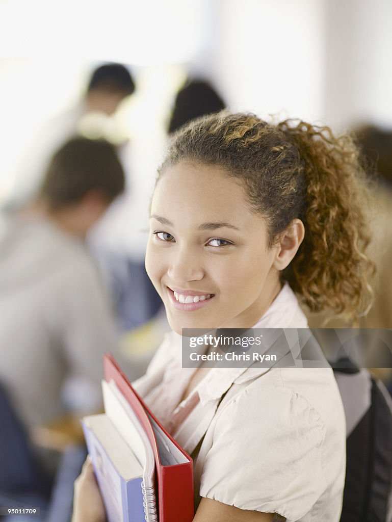 Smiling college student holding books