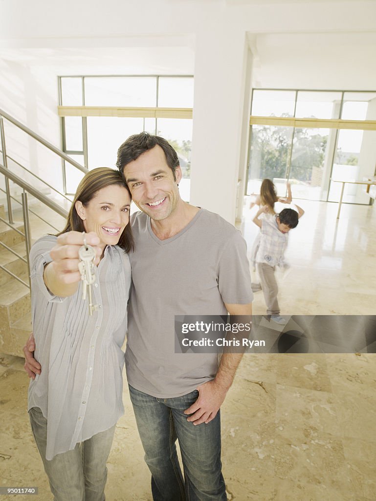 Happy couple holding keys in new house