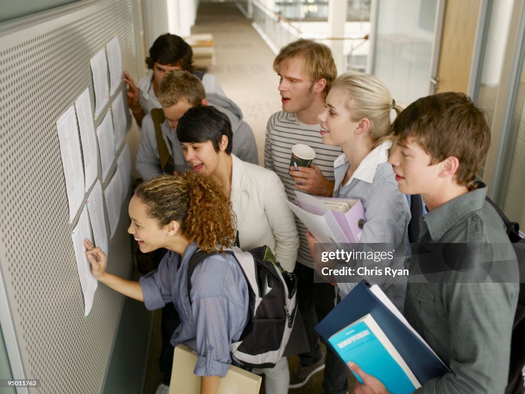 College students checking test scores in corridor