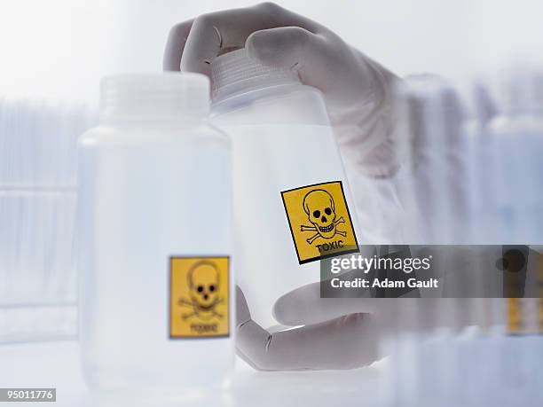 scientist holding bottle with toxic label - nocivo descripción física fotografías e imágenes de stock