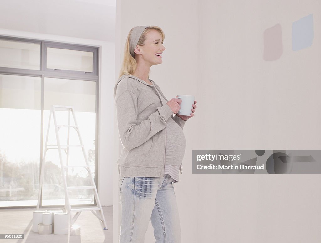 Pregnant woman looking at paint samples on nursery wall