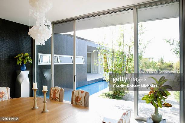 modern dining room overlooking swimming pool - glass door stock pictures, royalty-free photos & images