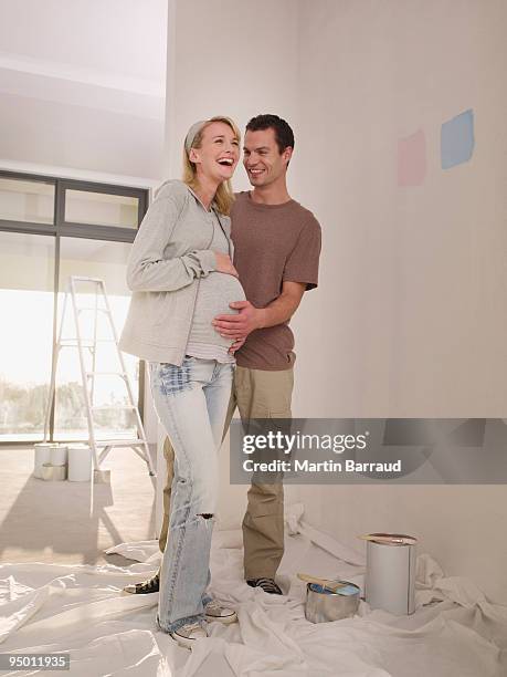 pregnant woman and man painting nursery - young family at home stock pictures, royalty-free photos & images