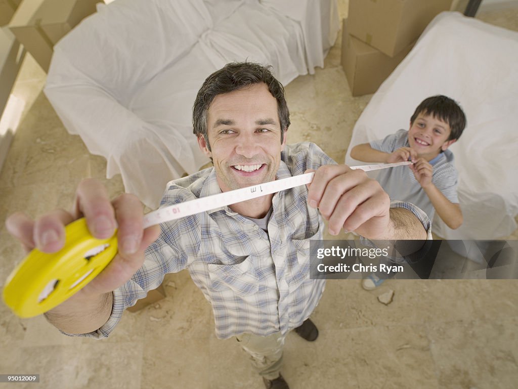 Father and son holding measuring tape
