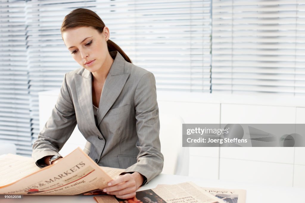 Businesswoman reading newspaper