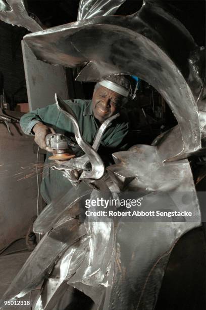 Noted African-American sculptor Richard Hunt grinds and polishes a metal sculpture while at a foundry or studio, Chicago, IL, 2000.