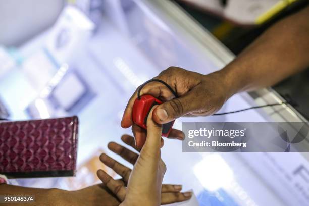 Vendor scans a customer's fingerprint while registering a new data connection on a Bharti Airtel Ltd. App for a customer at a sim card store in...