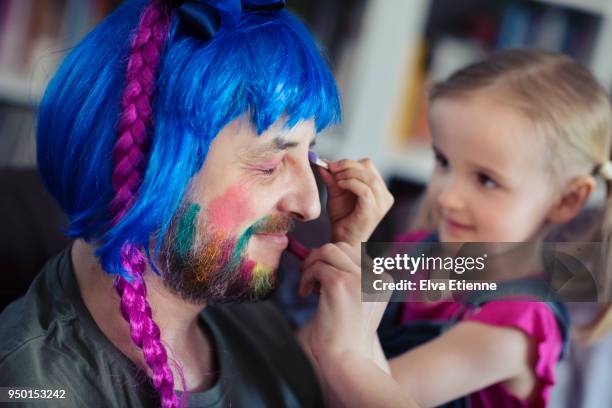 girl (4-5) having fun putting makeup and wig on her father - männlichkeit stock-fotos und bilder