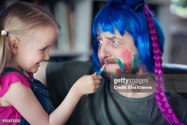 girl (4-5) having fun putting makeup on her bemused father - creative makeup stockfoto's en -beelden