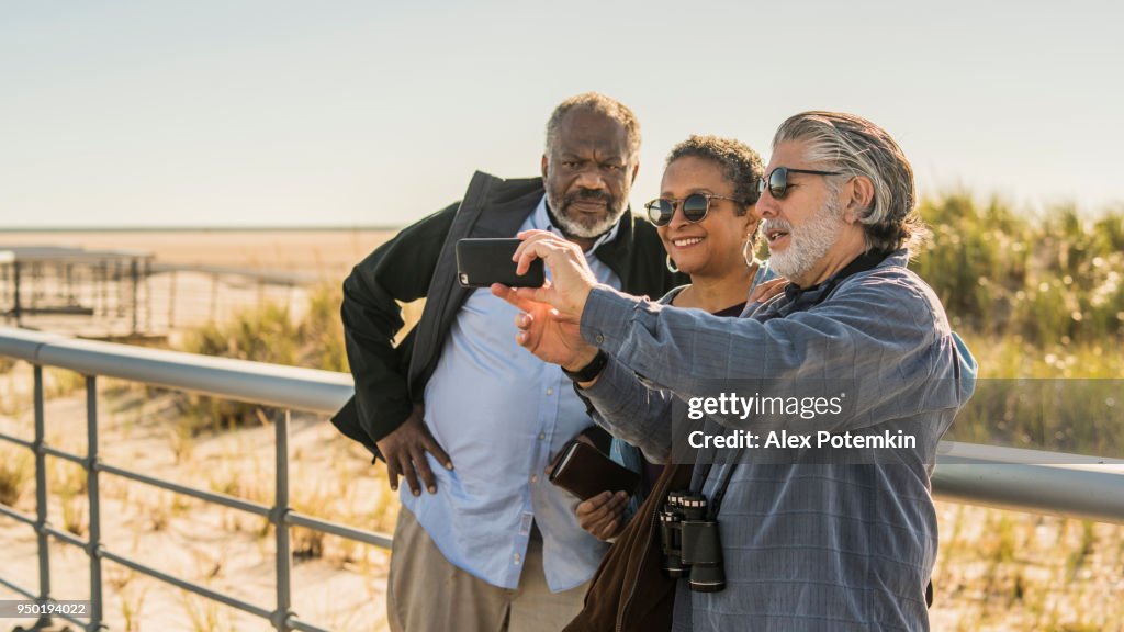 Gli amici anziani si fanno selfie in spiaggia