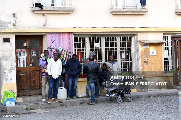 Migrants stand outside a center where they find shelter after crossing the border from Italy to France on April 23, 2018 in Briancon, southeastern...