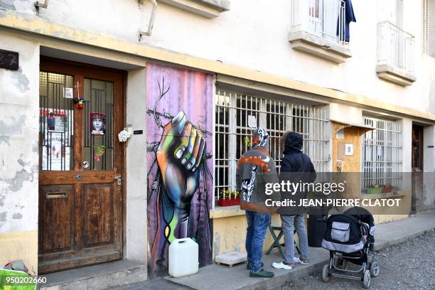 Migrants stand outside a center where they find shelter after crossing the border from Italy to France on April 23, 2018 in Briancon, southeastern...