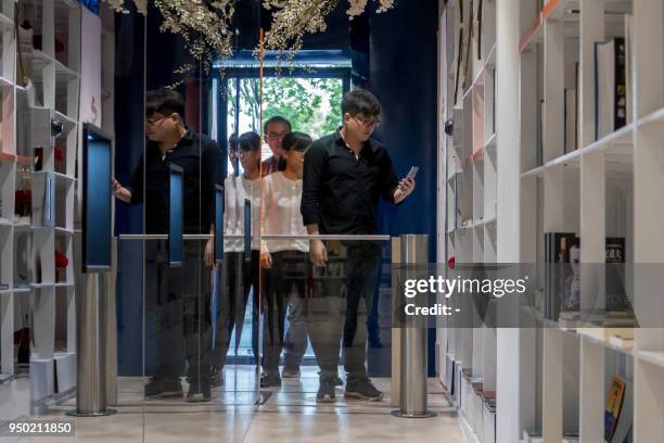 Man prepares to pass the entrance of a smart bookstore as he scans a QR code with his smart phone during the World Book Day in Shanghai on April 23,...