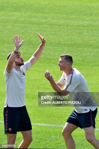 As Roma's players defender Kostas Manolas and striker Edin Dzeko joke as they take part in a training session, on the eve of the Champions League...