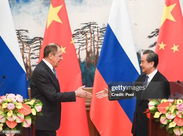 Russia's Foreign Minister Sergei Lavrov and Chinese State Councilor and Foreign Minister Wang Yi move for a handshake after their press conference at...