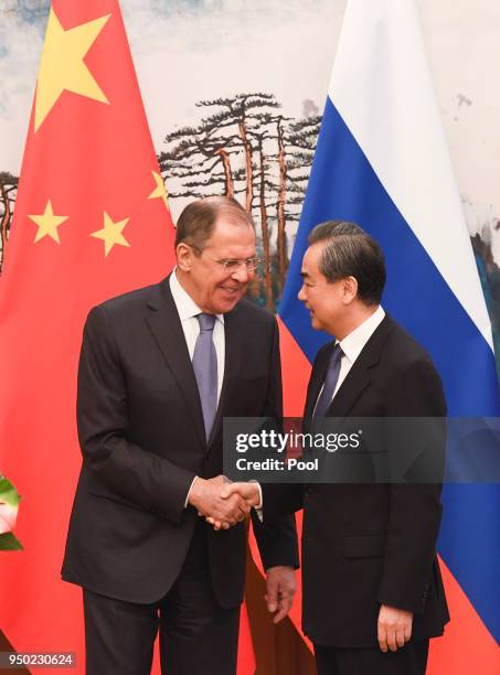 Russia's Foreign Minister Sergei Lavrov and Chinese State Councilor and Foreign Minister Wang Yi shake hands as they end their press conference at...